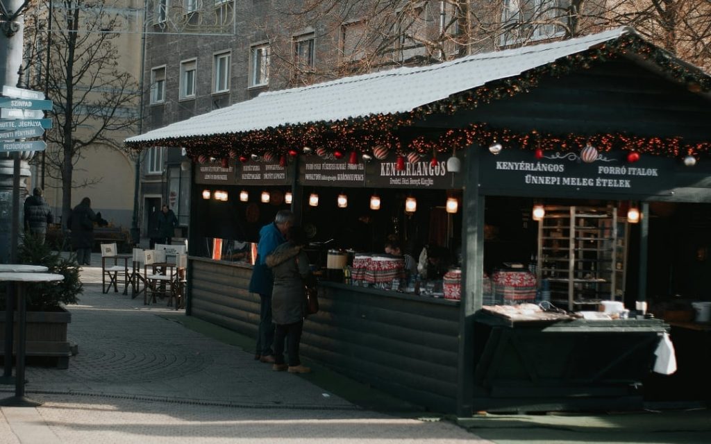 Drewniane kramy jarmarku bożonarodzeniowego przykryte śniegiem w Budapeszcie