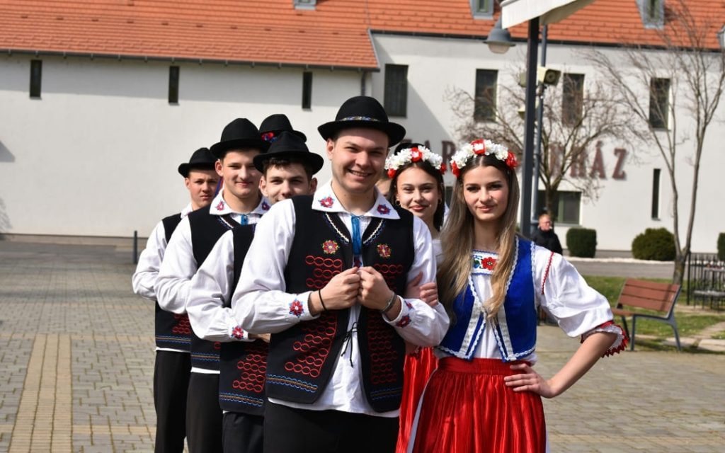 Młodzi tancerze w tradycyjnych węgierskich strojach ludowych na placu przed budynkiem kultury