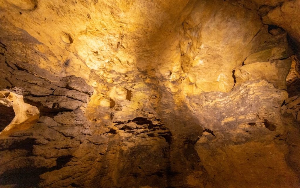 Oświetlone skalne ściany Jaskini Pál-völgyi w Budapeszcie w ciepłym żółtym świetle