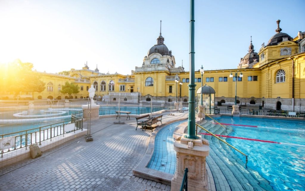 Puste baseny łaźni Széchenyi w Budapeszcie o wschodzie słońca z żółtą neorenesansową fasadą
