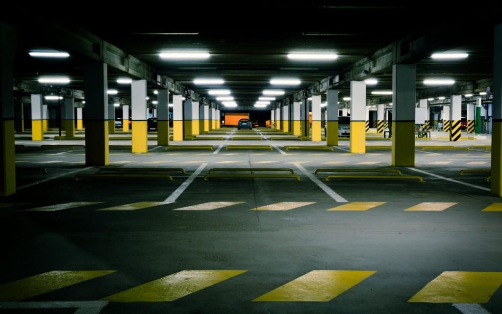 Ciemny parking podziemny z żółtymi oznaczeniami i sztucznym oświetleniem