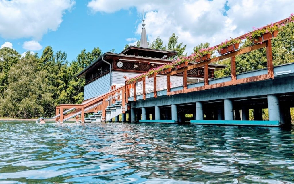 Drewniany pawilon z kwiatami nad turkusową wodą termalnego jeziora Hévíz na Węgrzech