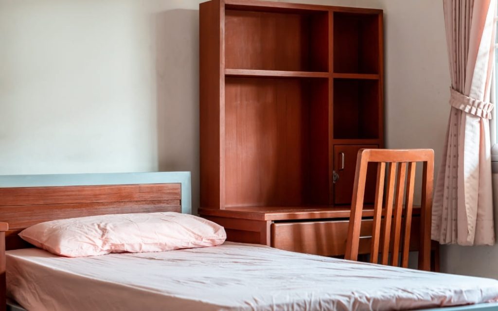 Elegancki pokój hotelowy w ciepłej drewnianej kolorystyce z szafą i lampą