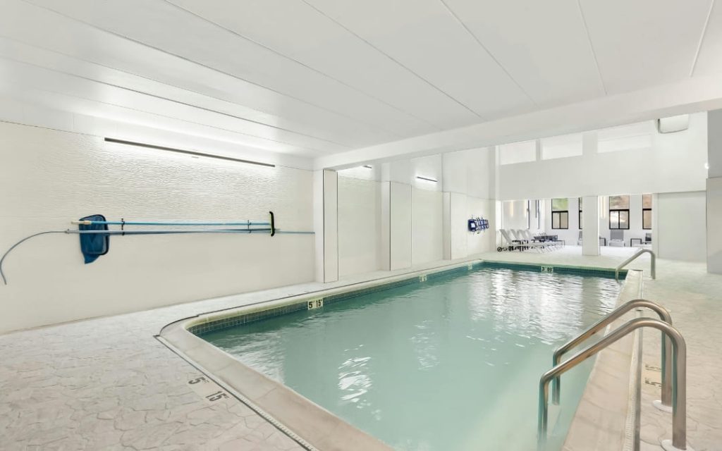 Jasny kryty basen hotelowy z błękitną wodą i białymi ścianami