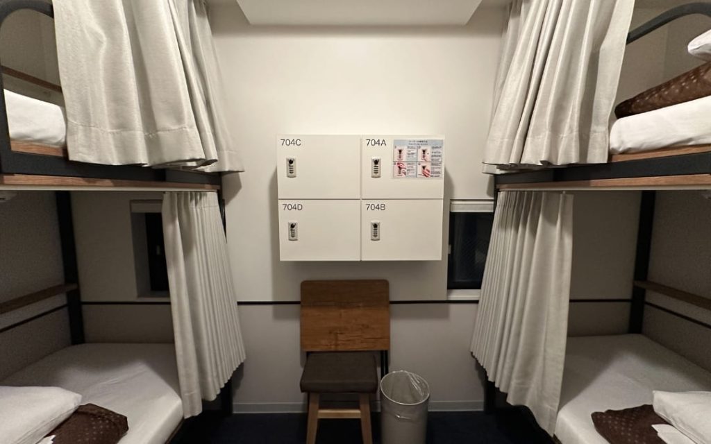 Jasny pokój hostelowy z łóżkami piętrowymi i białą pościelą