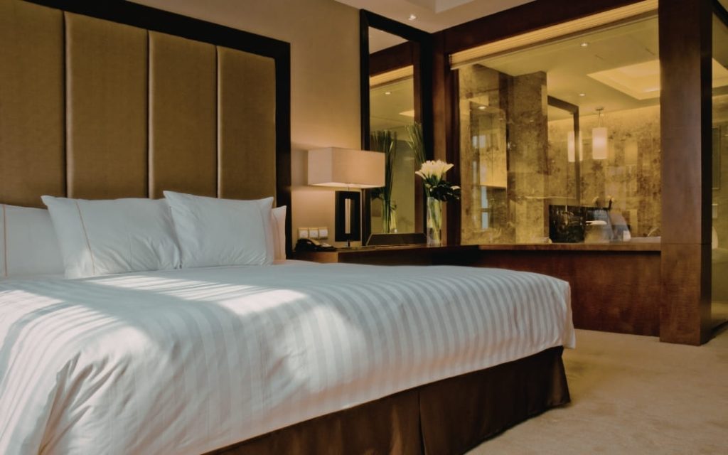 Przytulny pokój hotelowy z ciemniejszą kolorystyką i starannie ułożonym łóżkiem