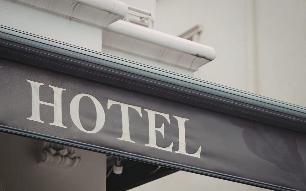 Zbliżenie na metalowy szyld z napisem _Hotel_ na elewacji budynku