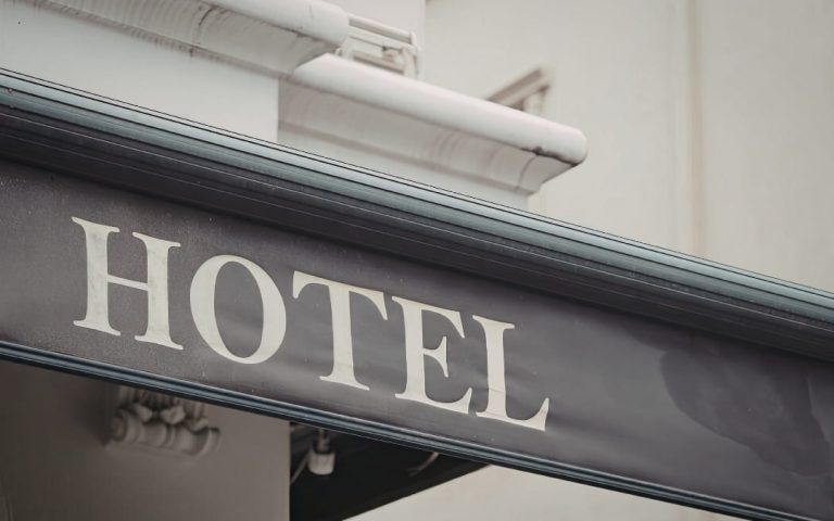 Zbliżenie na metalowy szyld z napisem _Hotel_ na elewacji budynku