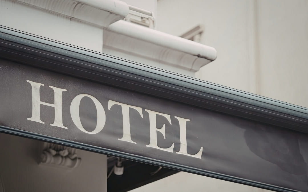 Zbliżenie na metalowy szyld z napisem _Hotel_ na elewacji budynku