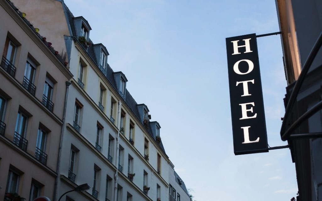 Zbliżenie na pionowy szyld _Hotel_ na klasycznej kamienicy