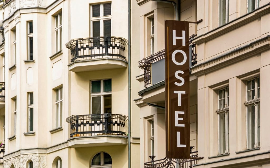 Zewnętrzna fasada budynku hostelu z szyldem i balkonami na elewacji