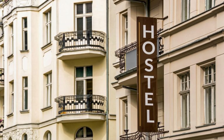 Zewnętrzna fasada budynku hostelu z szyldem i balkonami na elewacji