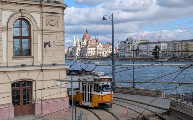 Żółty tramwaj na nabrzeżu Dunaju w Budapeszcie z Parlamentem węgierskim w tle
