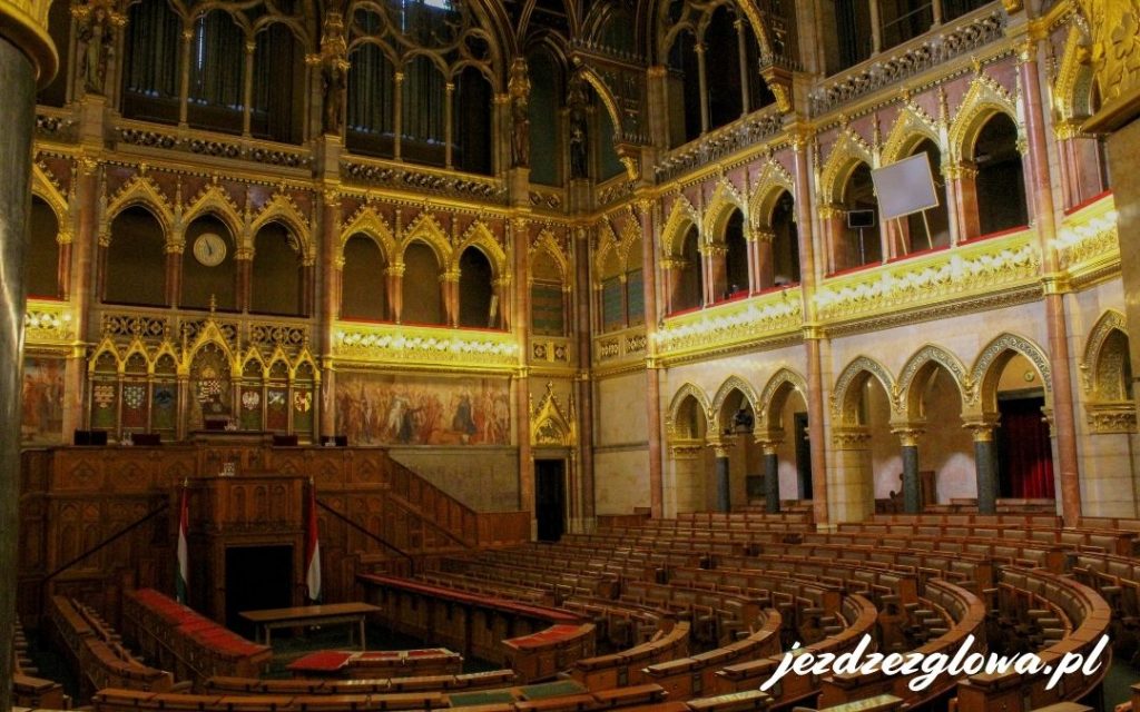 Sala posiedzeń Parlamentu Węgier z drewnianymi ławami i złotymi zdobieniami