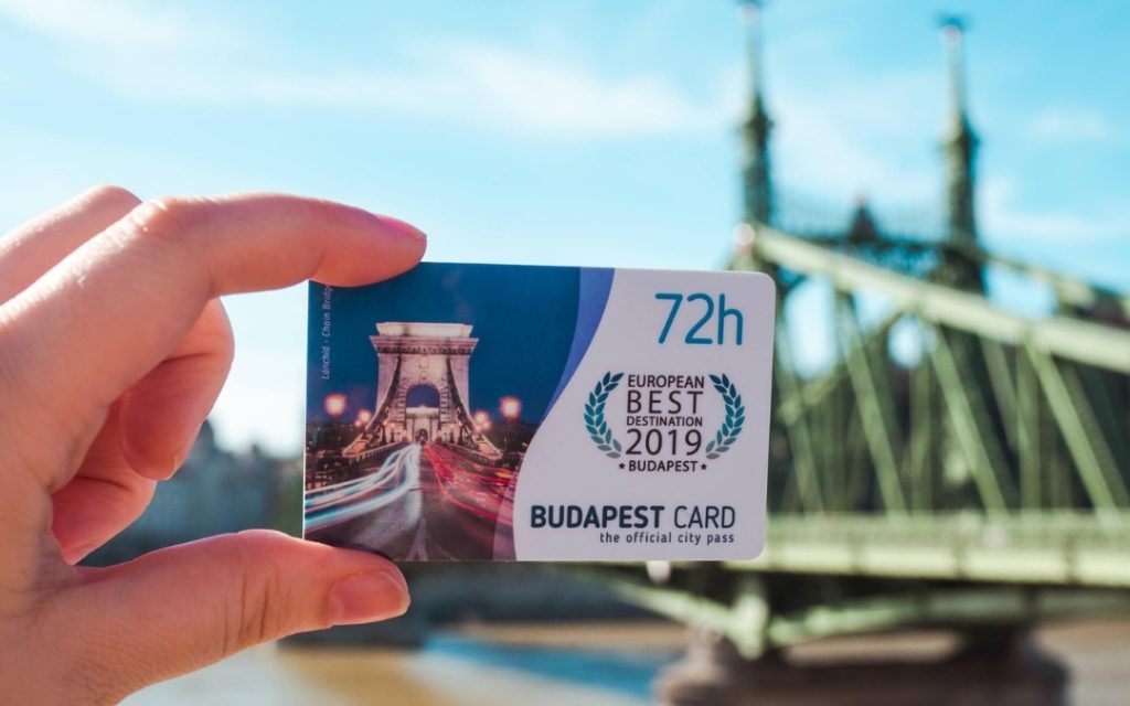 Karta Budapest Card 72h trzymana w dłoni na tle Mostu Wolności w Budapeszcie