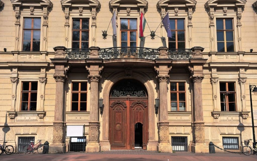 Reprezentacyjna fasada pałacu przy Alei Andrássyego w Budapeszcie z bogato zdobionym portalem i balkonem z żelazną balustradą