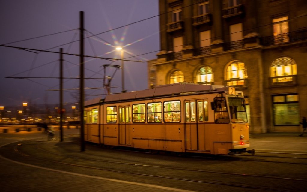 Żółty tramwaj linii 2 jadący wieczorem przez Budapeszt, oświetlony latarniami i światłami budynków