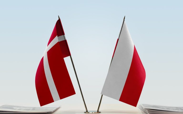 Flagi Danii i Polski, umieszczone obok siebie na masztach stołowych