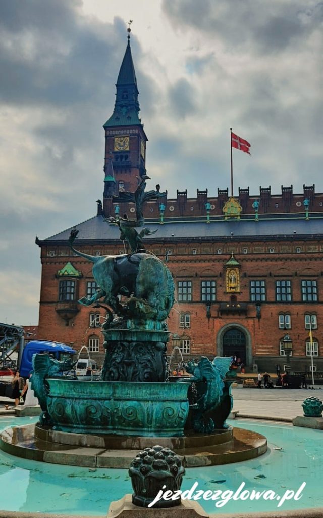Fontanna Smoka w centrum Kopenhagi, na tle Ratusza i wieży zegarowej