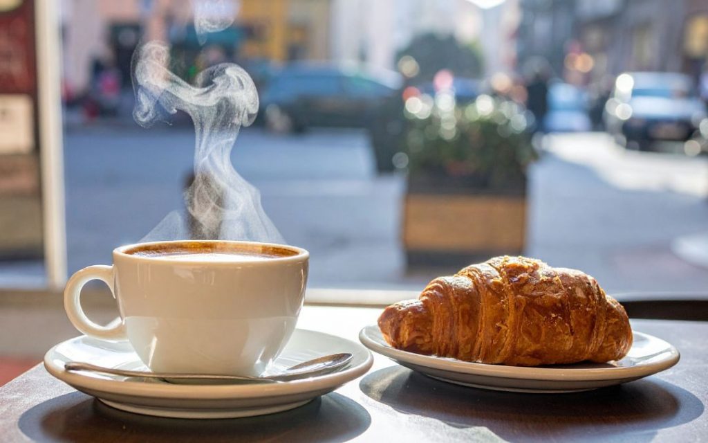 Klasyczne włoskie śniadanie - kawa z croissantem w miejskiej kawiarni