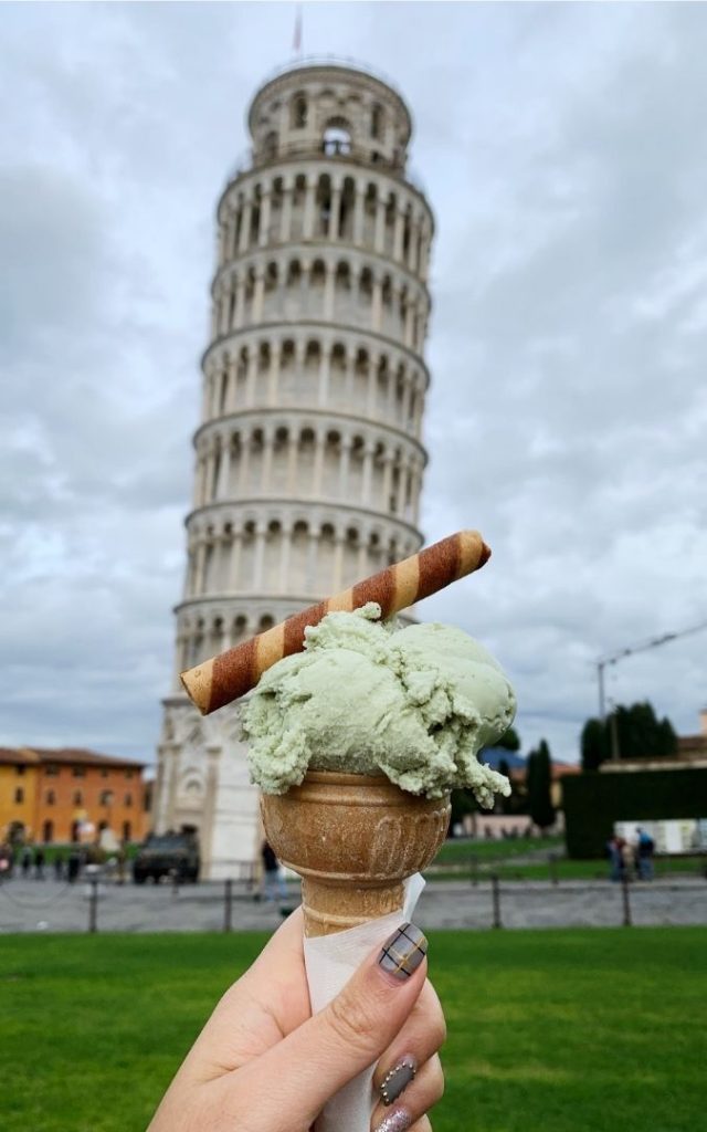 Lody w rożku trzymane przed Krzywą Wieżą w Pizie