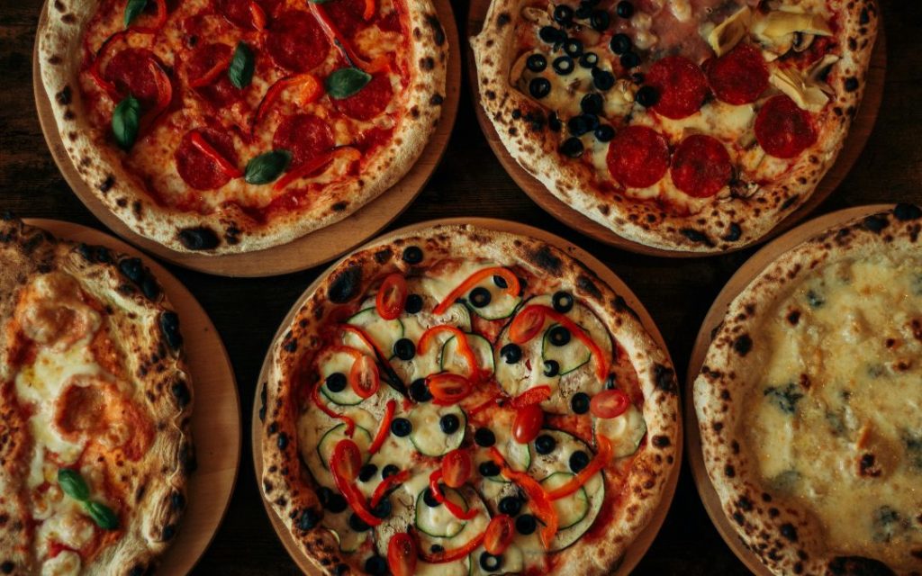 Różne rodzaje włoskiej pizzy ułożone obok siebie na stole