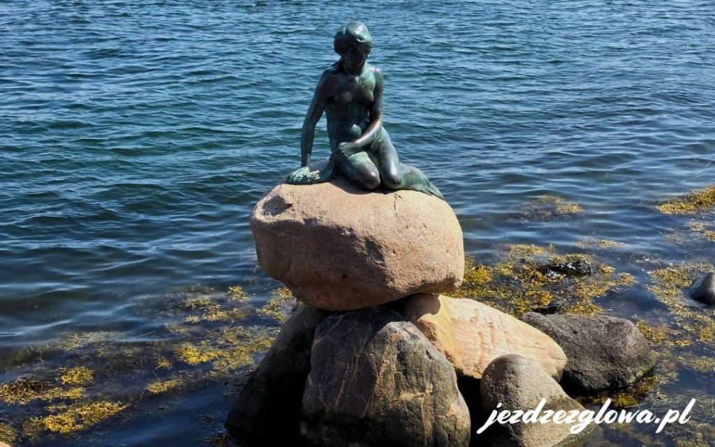 Rzeźba Małej Syrenki siedzącej na kamieniu nad brzegiem portu w Kopenhadze