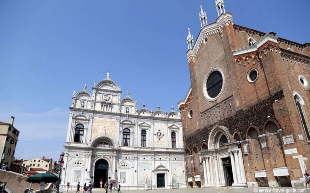 Włoska architektura w Wenecji biała, renesansowa fasada Scuola Grande di San Marco obok ceglanego, gotyckiego kościoła Santi Giovanni e Paolo, widziane na placu (Campo San Zanipolo).Włoska architektura w Wenecji biała, renesansowa fasada Scuola Grande di San Marco obok ceglanego, gotyckiego kościoła Santi Giovanni e Paolo, widziane na placu (Campo San Zanipolo).