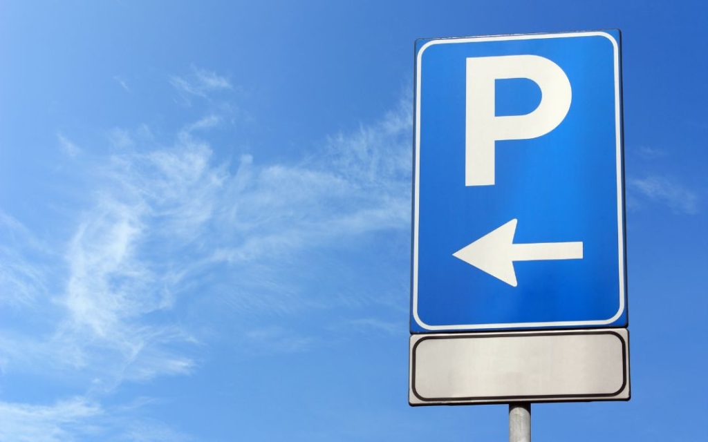Znak parkingu z białą literą P i strzałką w lewo