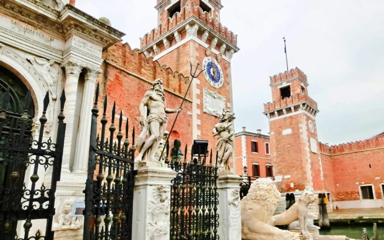 Główne wejście do Arsenału Weneckiego z fragmentem bramy, posągami antycznych lwów oraz ceglaną wieżą zegarową