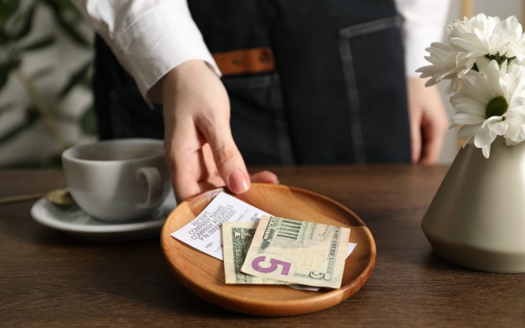 Ręka kelnerki odbierająca tackę z napiwkiem w restauracji