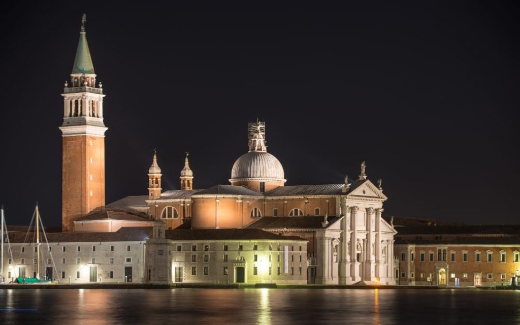 San Giorgio Maggiore w Wenecji o zmroku, z oświetloną fasadą i odbiciem świateł w wodzie