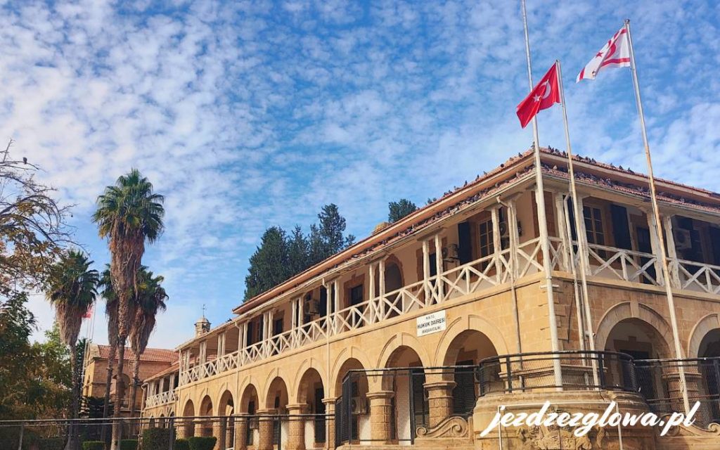 Budynek z historycznymi detalami, flaga Turcji powiewa na tle nieba i palm