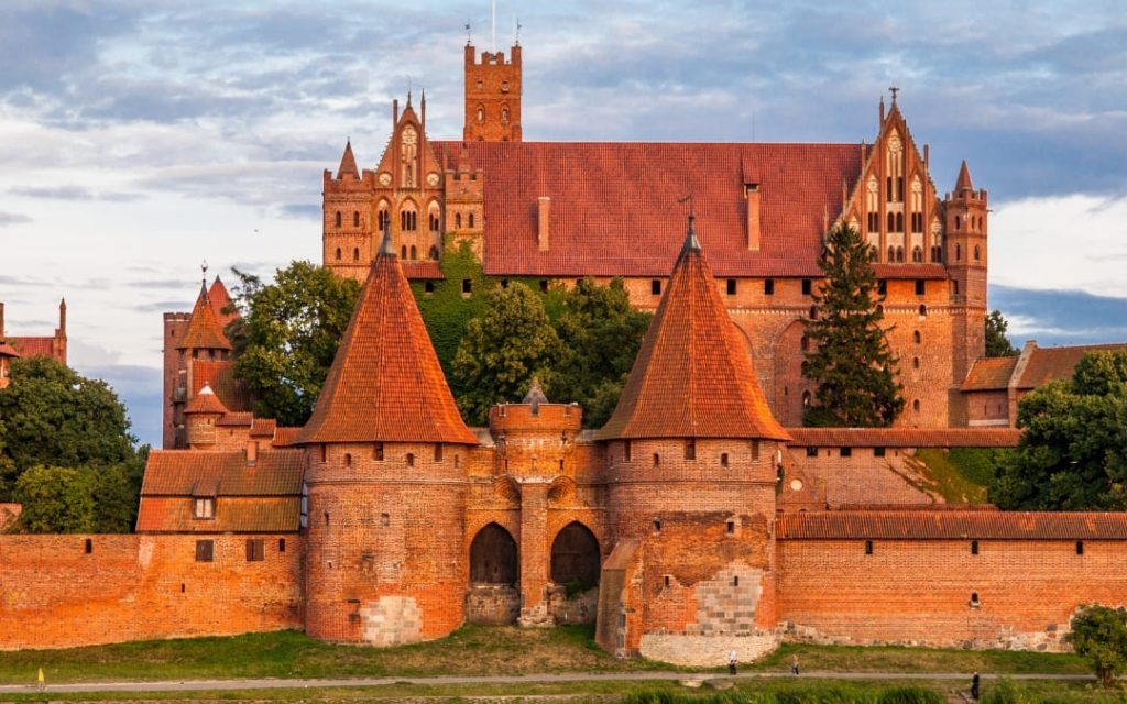 Gotycki Zamek w Malborku z czerwonej cegły z basztami i murami obronnymi o zmierzchu
