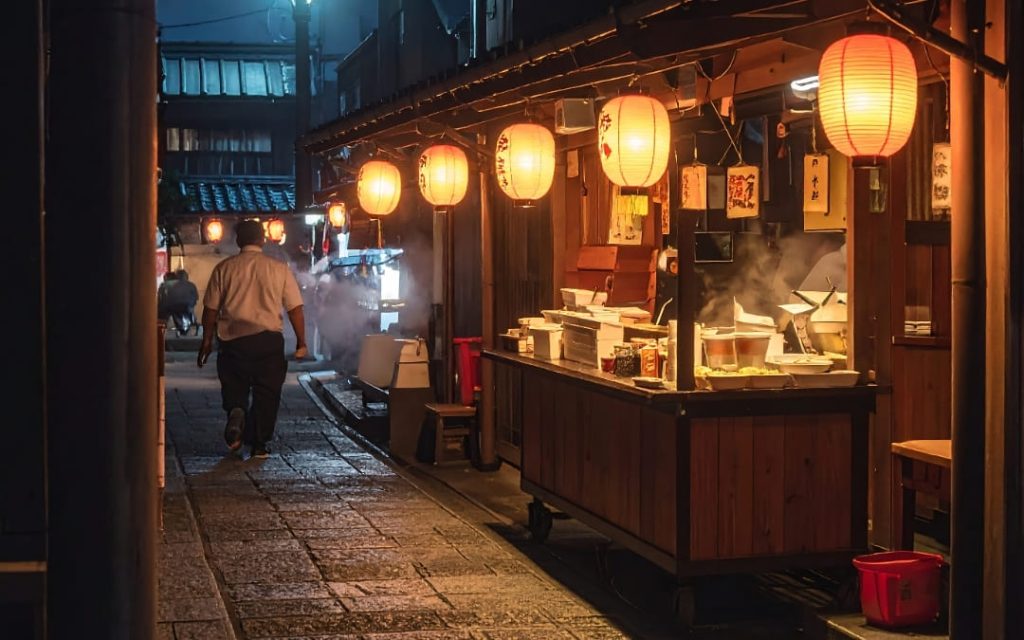 Japońskie stoisko uliczne yatai z czerwonymi lampionami i parującymi potrawami nocą