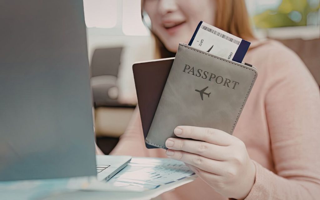 Kobieta trzymająca szare etui na paszport i bilet lotniczy