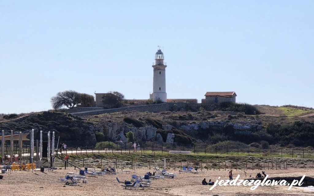 Latarnia morska na wzgórzu nad kamienistą plażą