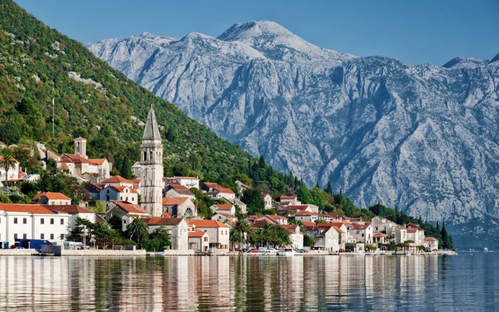 Miasteczko Perast w Czarnogórze z kościelną wieżą nad Zatoką Kotorską i górami w tle