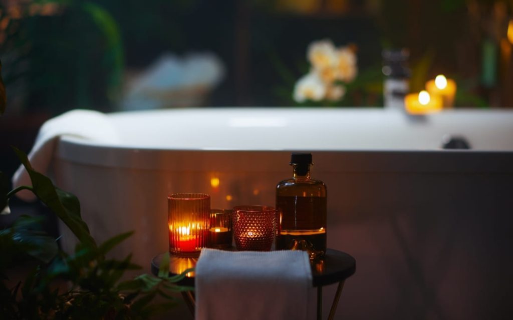 Nastrojowe domowe spa z zapalonymi świecami i białą wanną w ciemnym wnętrzu