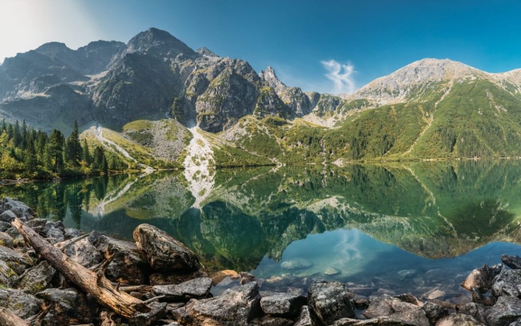 Panorama Morskiego Oka z lustrzanym odbiciem Tatr Wysokich w spokojnej wodzie latem