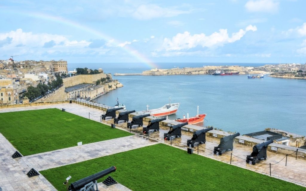Panorama portu w Valletcie z armatami i tęczą na niebie