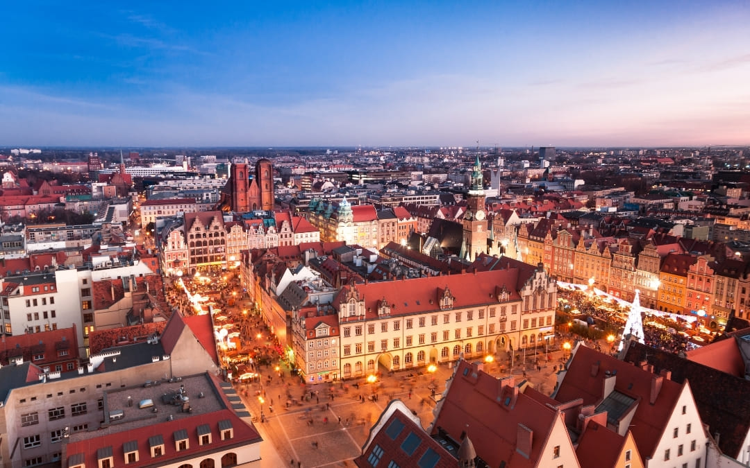 Rynek we Wrocławiu z oświetlonym jarmarkiem bożonarodzeniowym i ratuszem o zmierzchu
