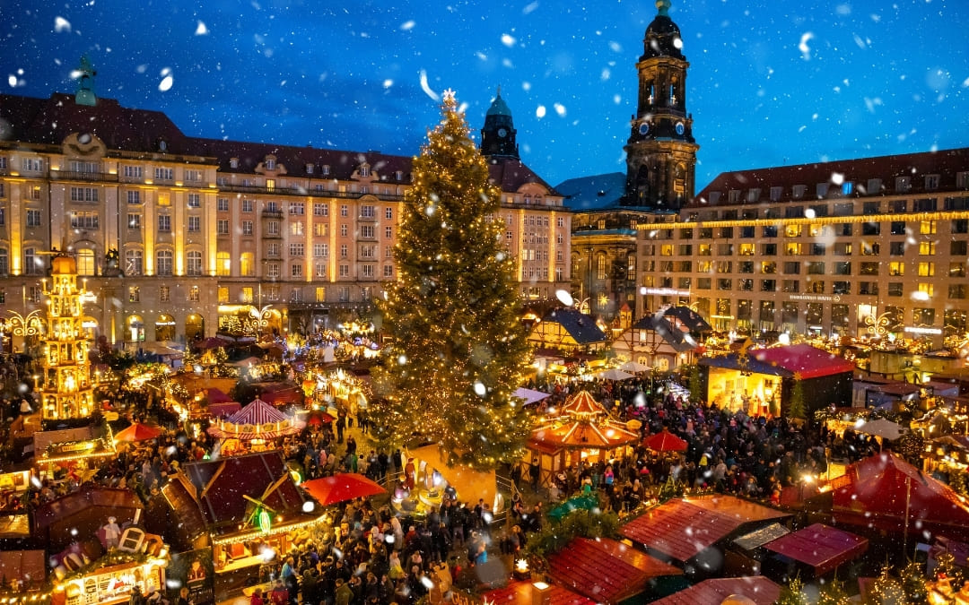 Striezelmarkt w Dreźnie z oświetloną choinką i tłumem podczas opadów śniegu nocą