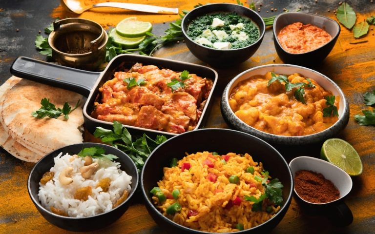 Zestaw indyjskich dań curry z ryżem, palak paneer i chlebem naan na ciemnym stole