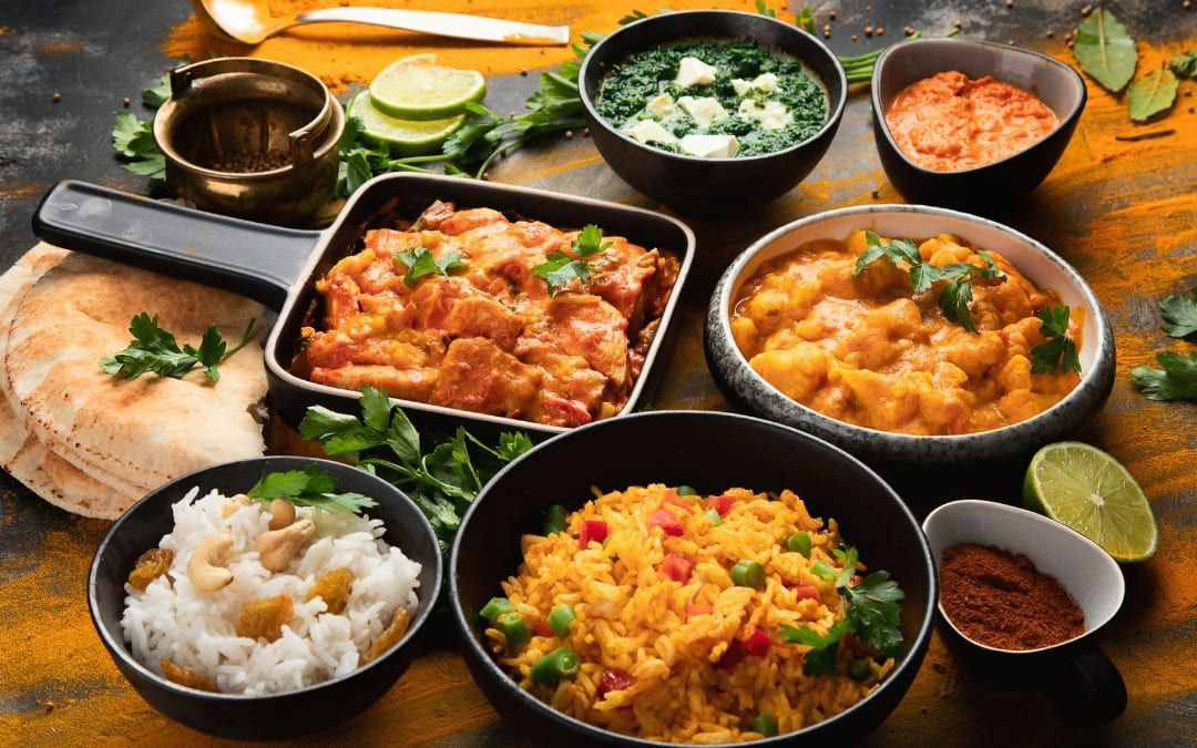 Zestaw indyjskich dań curry z ryżem, palak paneer i chlebem naan na ciemnym stole