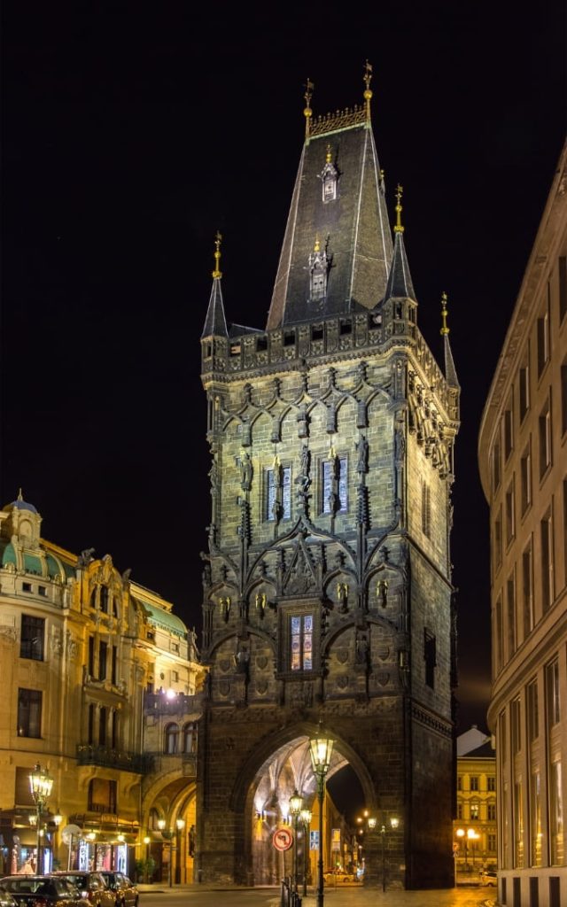 Brama Prochowa w Pradze nocą oświetlona ciepłym światłem latarni