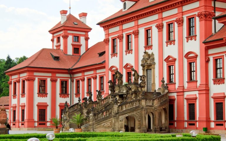 Czerwono-biała fasada Zamku Trojskiego w Pradze z barokową klatką schodową i rzeźbami