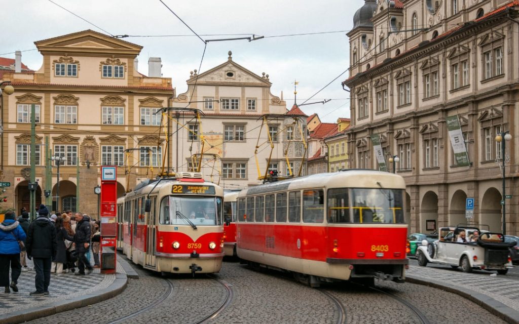 Dwa czerwone tramwaje linii 22 na brukowanym Rynku Małostrańskim w Pradze