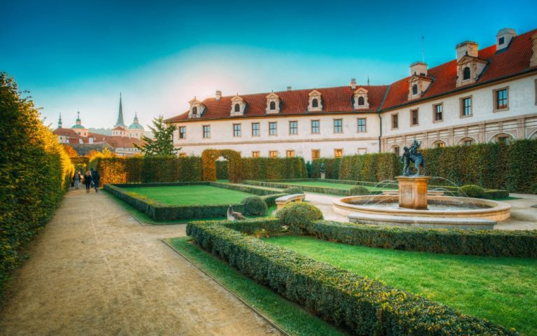 Geometryczne żywopłoty i fontanna w Ogrodzie Wallensteńskim w Pradze o zachodzie słońca