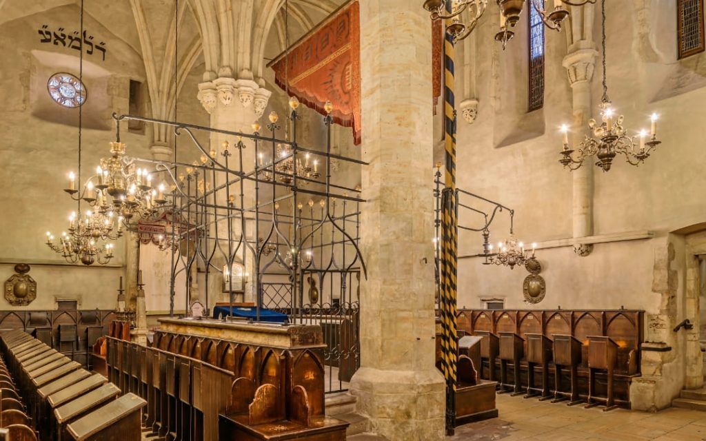 Gotyckie wnętrze Staronowej Synagogi w Pradze z żyrandolami i drewnianymi ławami